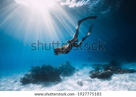 Woman freediver glides with fins. over sandy sea. Freediving and beautiful sunlight in blue ocean Royalty-Free Stock Photo #1927775183