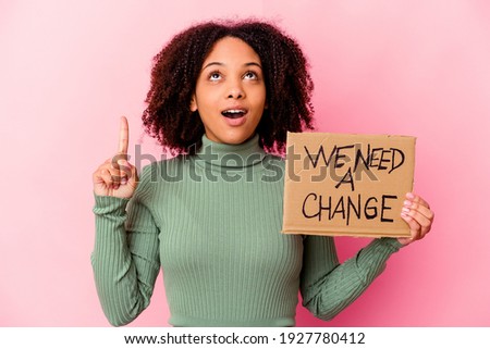 Young african american mixed race woman holding an inspiring message cardboard pointing upside with opened mouth.