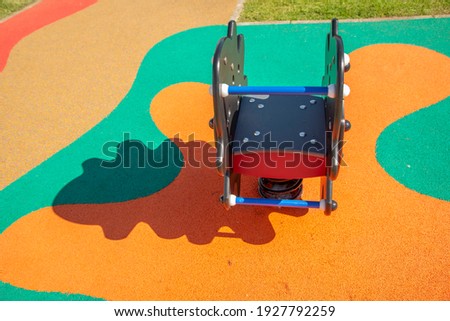 Children's playground with animal-shaped toys and figures with colorful spring and soft rubber floor for children's falls on a sunny day with the shadows hinting at the figure.