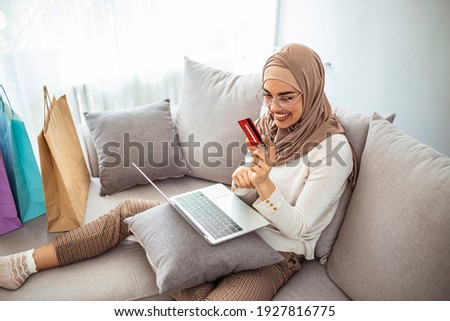 Arab woman making online purchase on laptop. Portrait of happy woman purchasing product via online shopping. Pay using credit card. Muslim woman online shopping