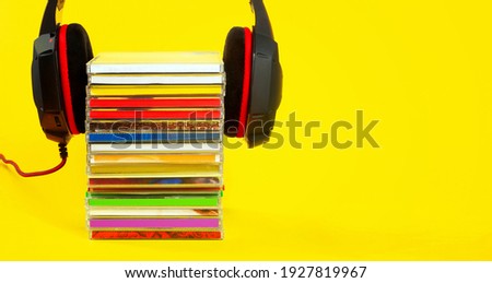 Headphones on a stack of CDs on a yellow background.Copy space.