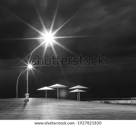 Tel Aviv, Israel, The old port (Namal Tel Aviv) at night time. Black and white ong exposure picture of the umbrellas area with sparkling street lights above it.