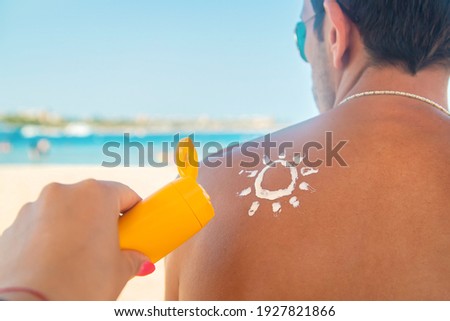 The girl on the beach applies sunscreen to the skin of a man. Selective focus. nature. Royalty-Free Stock Photo #1927821866