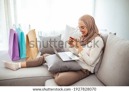 Arab woman making online purchase on laptop. Portrait of happy woman purchasing product via online shopping. Pay using credit card. Muslim woman online shopping