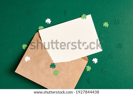 Saint Patricks day greeting card mockup with envelope and paper shamrock on green background, copy space