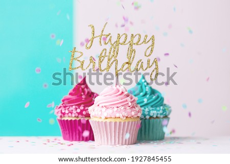 Pink and blue birthday cupcakes with happy birthday sign and confetti