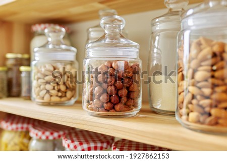 Kitchen pantry, wooden shelves with jars and containers with food, food storage. Jars with hazelnuts, pistachios, almonds