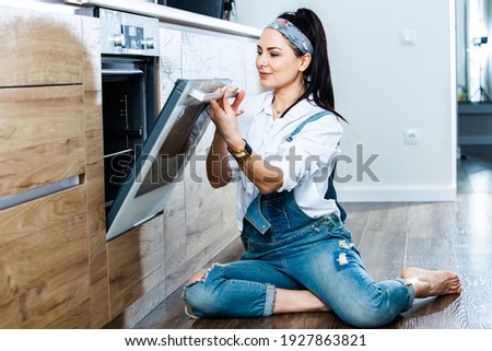 Beautiful european housewife in the kichan. Woman wearing jeans at home.