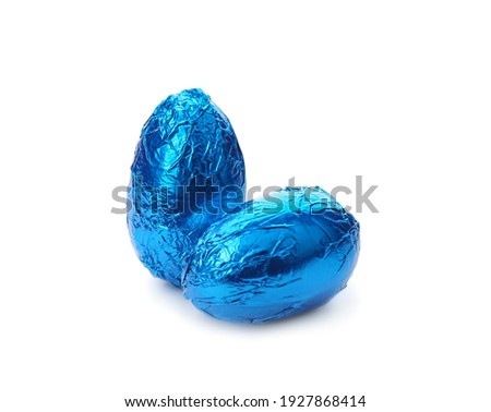 Chocolate eggs wrapped in blue foil on white background