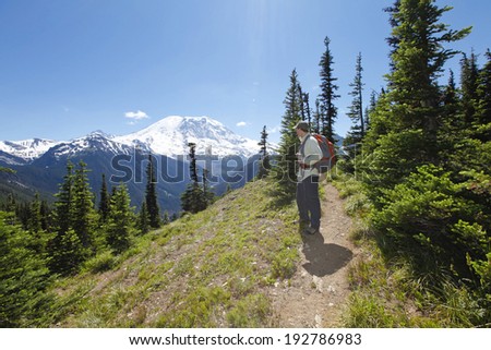 Young man enjoying the stunning scenic view of mountain Rainer on hiking trail. Washington, Seattle