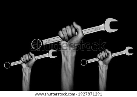 black and white photo. three spanners in the women's hands. hands holds a wrenches on a gray background. Combination wrench. big chrome vanadium spanner in the hand. women's work