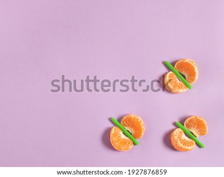 Slices of tangerine with green sticks like butterflies,  on pastel pink background flat lay