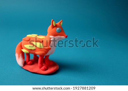 Do-it-yourself plasticine figurine in the shape of an animal fox on a blue background.