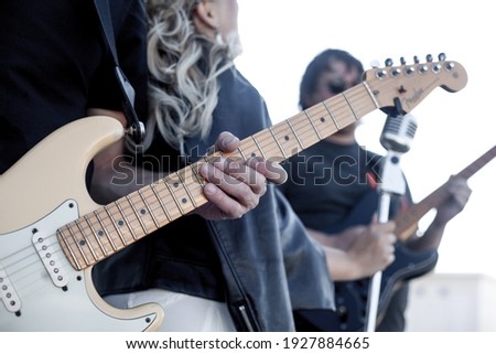 Close-up of hands playing guitar. Group of street musicians, two guitarists and a vocalist sign in the street and play thier own musik for lowers to practice and make money 