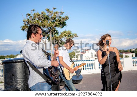 Group of street musicians, two guitarists and a vocalist sign in the street and play thier own musik for lowers to practice and make money 