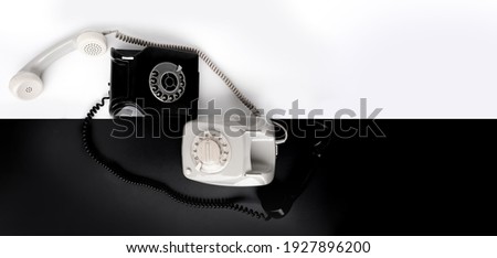 two vintage telephone sets with dial in retro style on a black, white background, concept of old communication technologies, harmony of relationships, masculine and feminine principles, yin yang