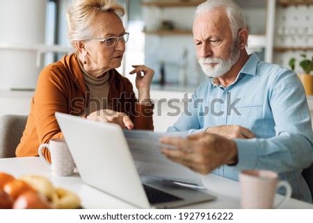 Frustrated senior couple sitting at home and  checking  their home finances Royalty-Free Stock Photo #1927916222