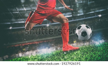 Close up of a soccer scene at night match with player in a red uniform kicking the ball with power Royalty-Free Stock Photo #1927926191