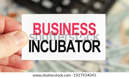 Motivational words: BUSINESS INCUBATOR. Man holds a piece of paper with the text: BUSINESS INCUBATOR. Business and finance concept
