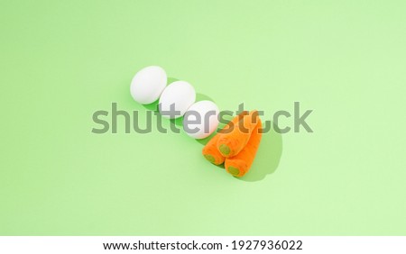 2021 Easter minimal composition. Three white eggs and three carrots on a pastel green background. Minimal creative flat lay composition. 