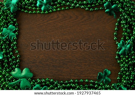 Saint Patrick's day frame with green beads and shamrock on wooden background.
