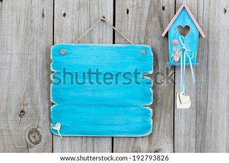 Antique blank teal blue sign with blue and pink birdhouse with wood hearts and flowers hanging on rustic wooden fence