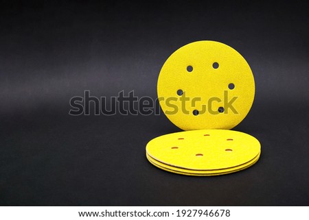 Sandpaper for sanding wood, on a black background. A stack of yellow round sandpaper. Copy space Royalty-Free Stock Photo #1927946678