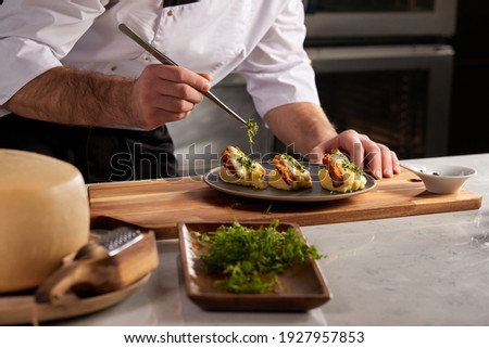 Cropped photo Close-up hands of male cook adding greens finishing dish, decorating meal in the end. gastronomy, food, nutrition, cafe concept Royalty-Free Stock Photo #1927957853