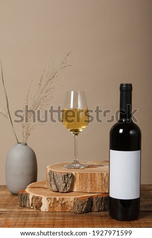 Blank white label mock up on black bottle of unlabeled wine on a wooden table. Alcohol bottle mockup presentation ready for logo design. Full drink bottle template with empty sticker.