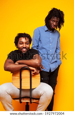 two african american guys posing cheerful together on yellow background, lifestyle people concept