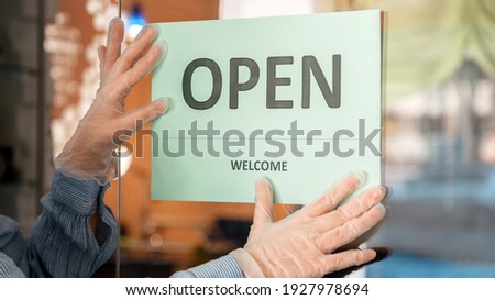 Green Sign Open welcome covid 19 lockdown reopen as new normal. Reopening sign Open on front door entrance. Woman in protective medical gloves hangs Open sign on door. Long web banner.