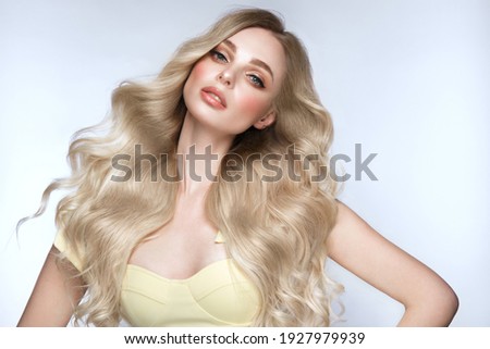 Beautiful blond girl with a perfectly curls hair, and classic make-up. Beauty face and hair. Picture taken in the studio.