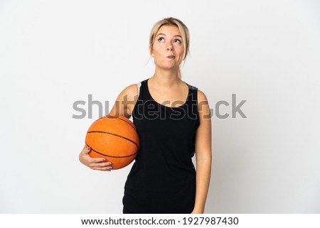 Young Russian woman playing basketball isolated on white background and looking up