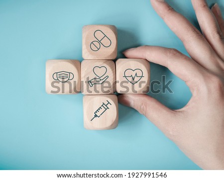 Hand woman choose wood cube stacking with icon healthcare medical on blue background, Health Insurance Concept
