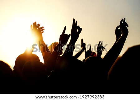 Raised hands of many people at a big mass event.