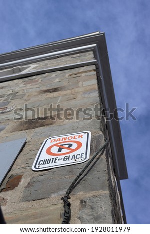 white metal sign written in french danger falling ice on the wall of a church
