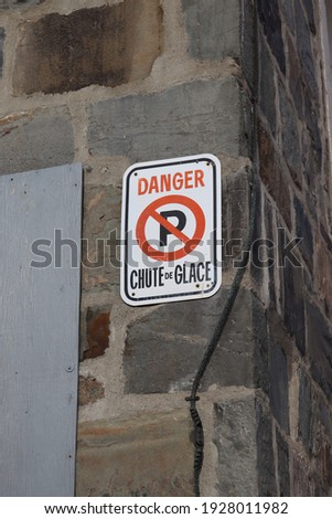 white metal sign written in french danger falling ice on the wall of a church
