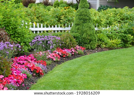 A lovely garden border around a neatly manicured lawn. Royalty-Free Stock Photo #1928016209