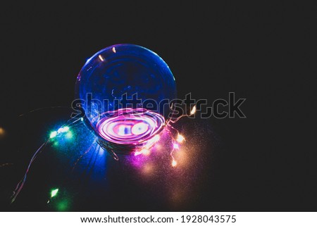 Swirling neon LED lights reflected in photo lens ball with dark background.