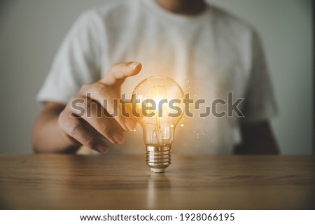 Hand holding light bulb on wood table. Concept of inspiration creative idea thinking and future technology innovation Royalty-Free Stock Photo #1928066195