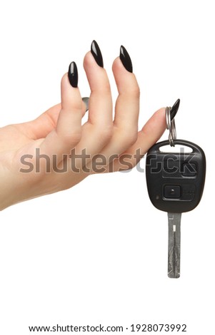 A female hand with a black nails manicure holds a black car key with her fingers. Car sharing concept. Isolated on white background.
