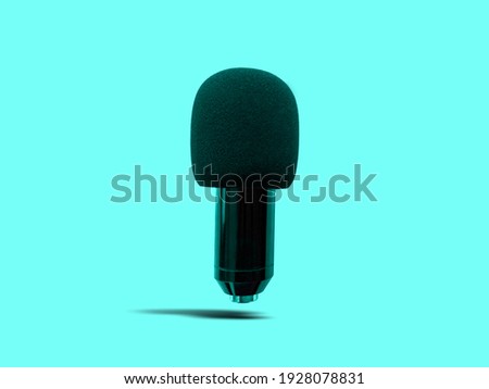 Floating Black Condenser Microphone with Foam Windshield isolated on Turquoise Background