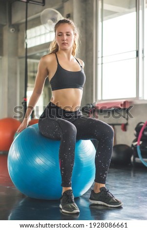 Young beautiful woman training pilates exercises with fit ball in fitness gym.