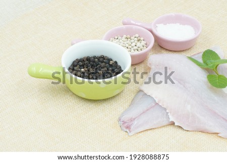 Raw fresh tilapia fillets with seasonings ready to be cooked,
