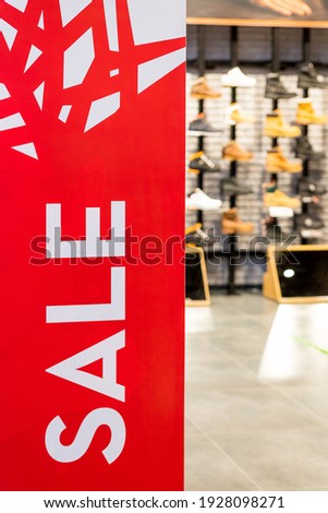 Red bright sale banner on anti-thieft gate sensor at retail shopping mall entrance. Seasonal discount offer .Discount information at store entrance, shopping season promotion.Large red panels.