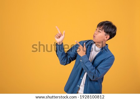 Asian man pointing his finger to look up. On orange background
