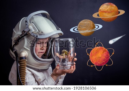 Child who dreams to be an astronaut. Open space with planet. Kid boy in helmet playing spaceman with plant in jar. Science