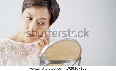 Middle aged Asian woman worrying about her facial skin. Rough skin. Beauty concept. Skin care. Royalty-Free Stock Photo #1928107130