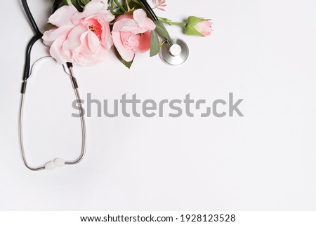 Bunch of rose flowers and stethoscope on white background. National Doctor's day. Happy nurse day. Top view with copy space Royalty-Free Stock Photo #1928123528