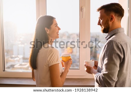 A man and woman drink tea near the window